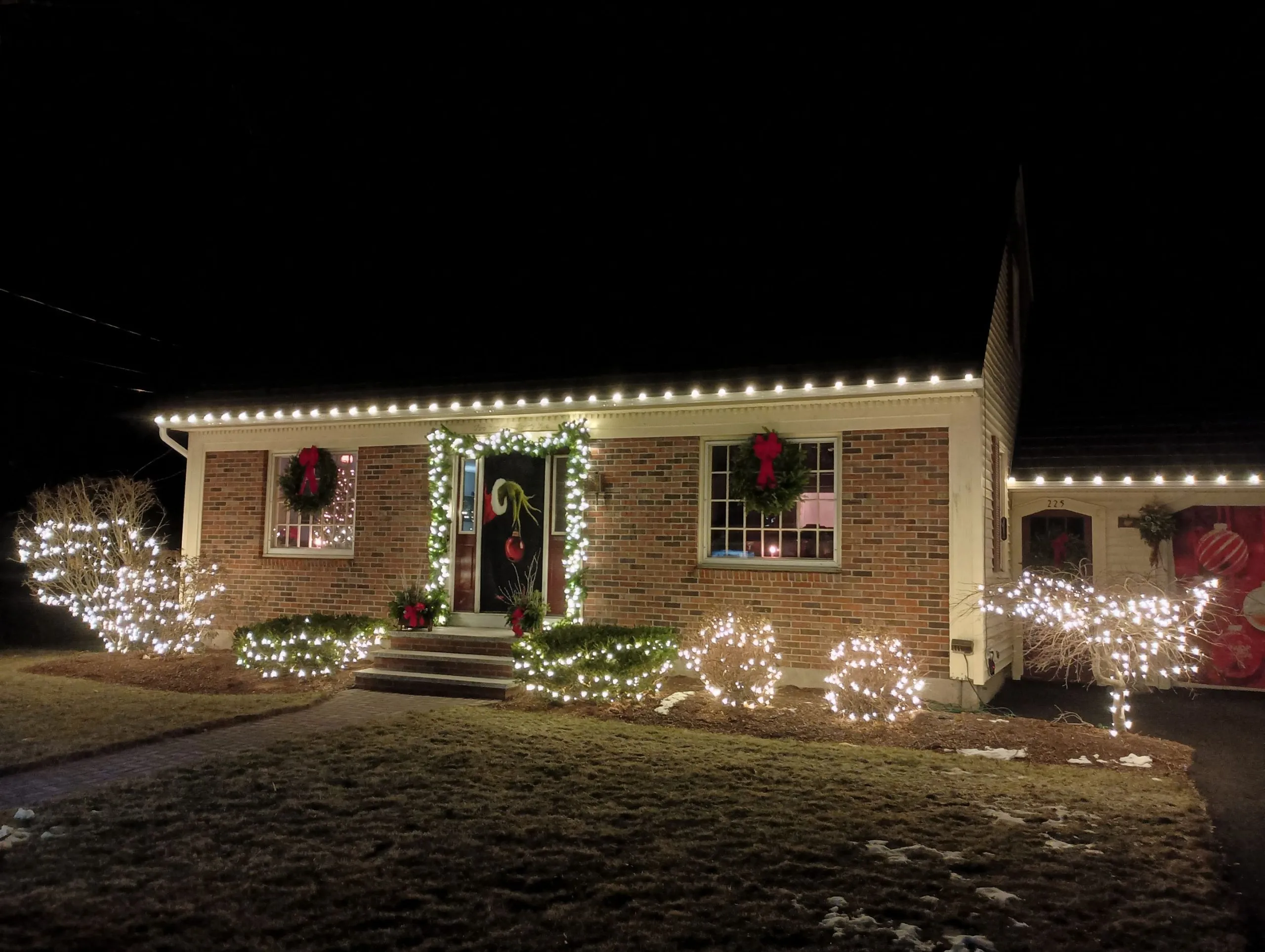 Warm-white holiday lights tracing the peaks and eaves of a New England home at night