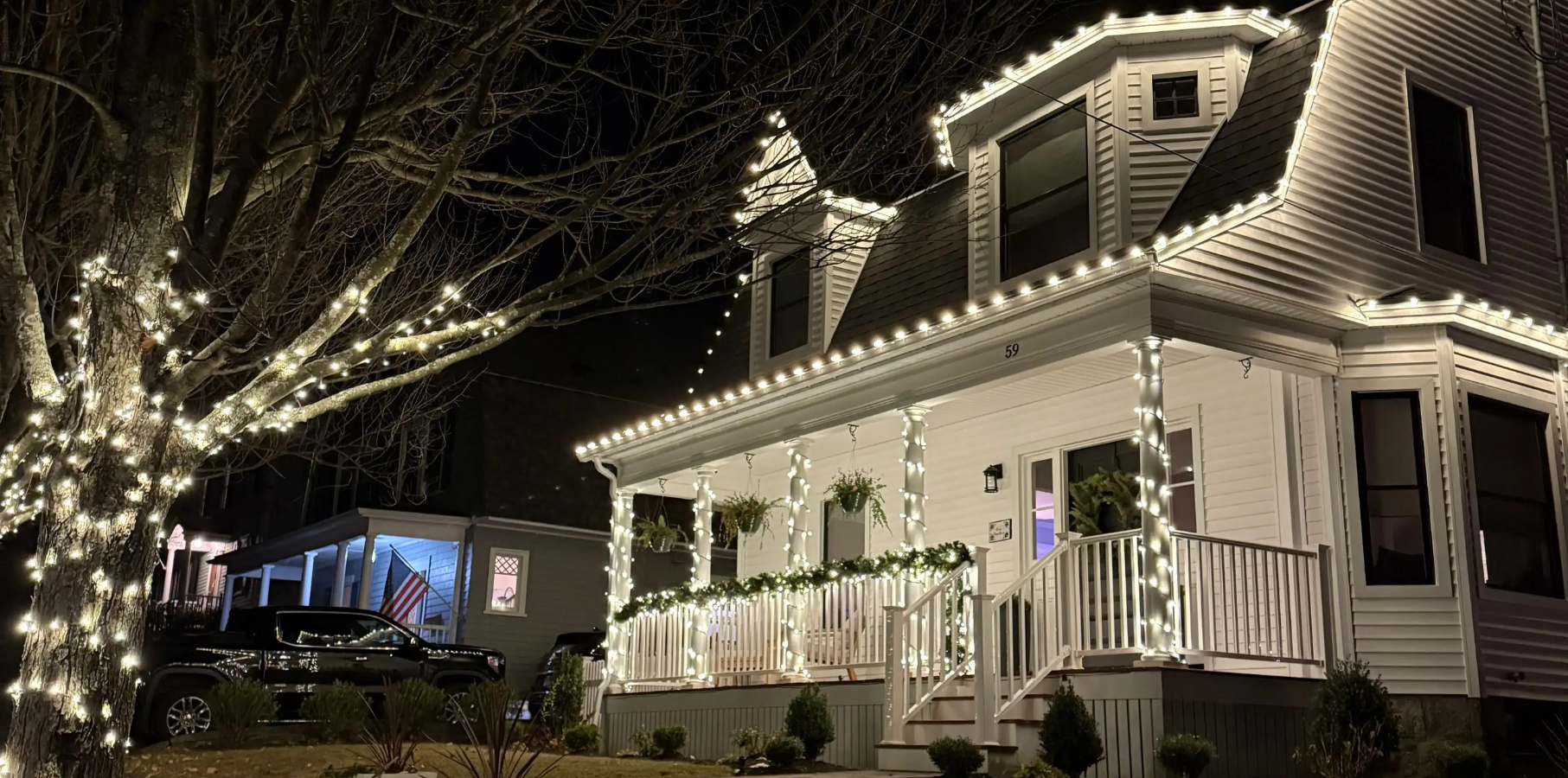 New England home fully outlined in warm-white lighting on a winter evening
