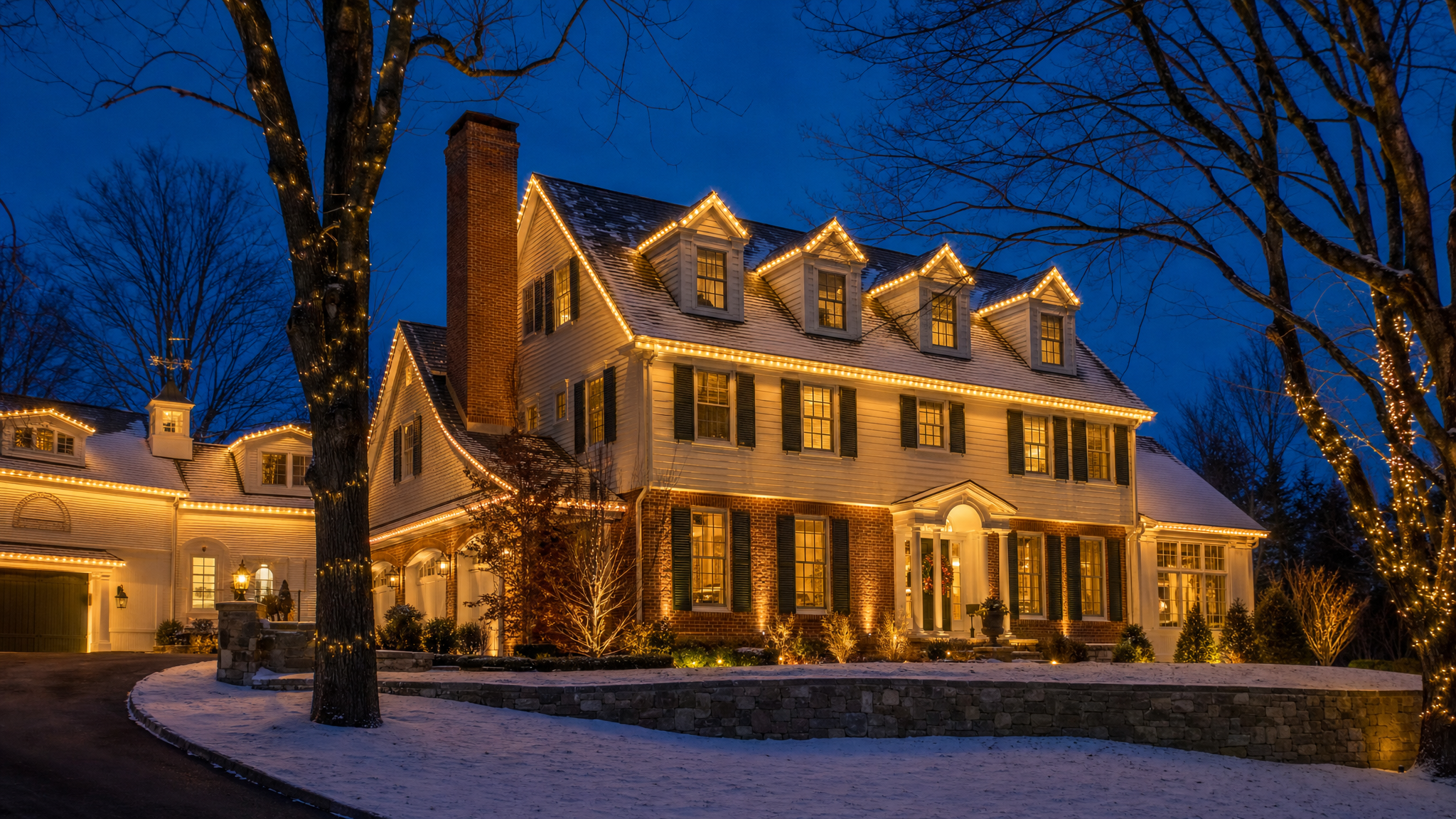 New England colonial home with warm amber roofline lighting at blue-hour twilight